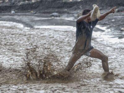 Un homme lutte contre les eaux déferlantes de la rivière La Digue pour rejoindre la douzième section de Petit-Goâve. Vendredi 31 octobre 2025. | © Jean Feguens Regala / AyiboPost